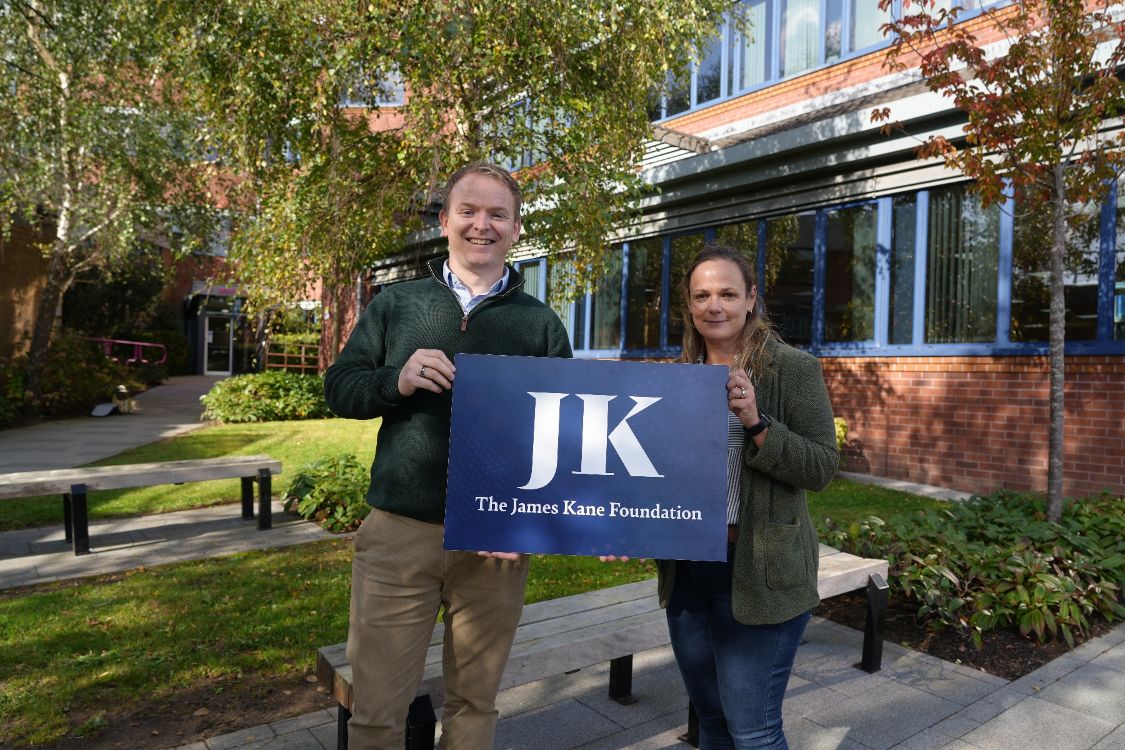 Two people holding a placard with JK - James Kane Foundation written on it